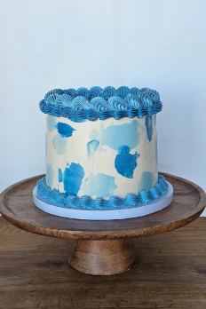 White buttercream cake with blue painted details and piped border